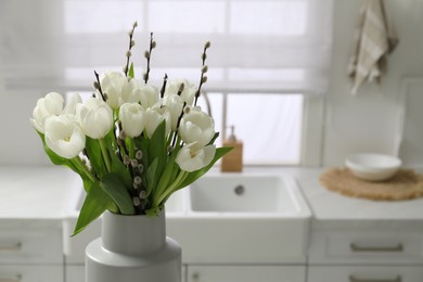 Photo of Beautiful bouquet of willow branches and tulips in vase indoors, space for text