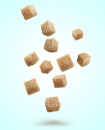 Image of Brown cane sugar cubes falling on light blue background