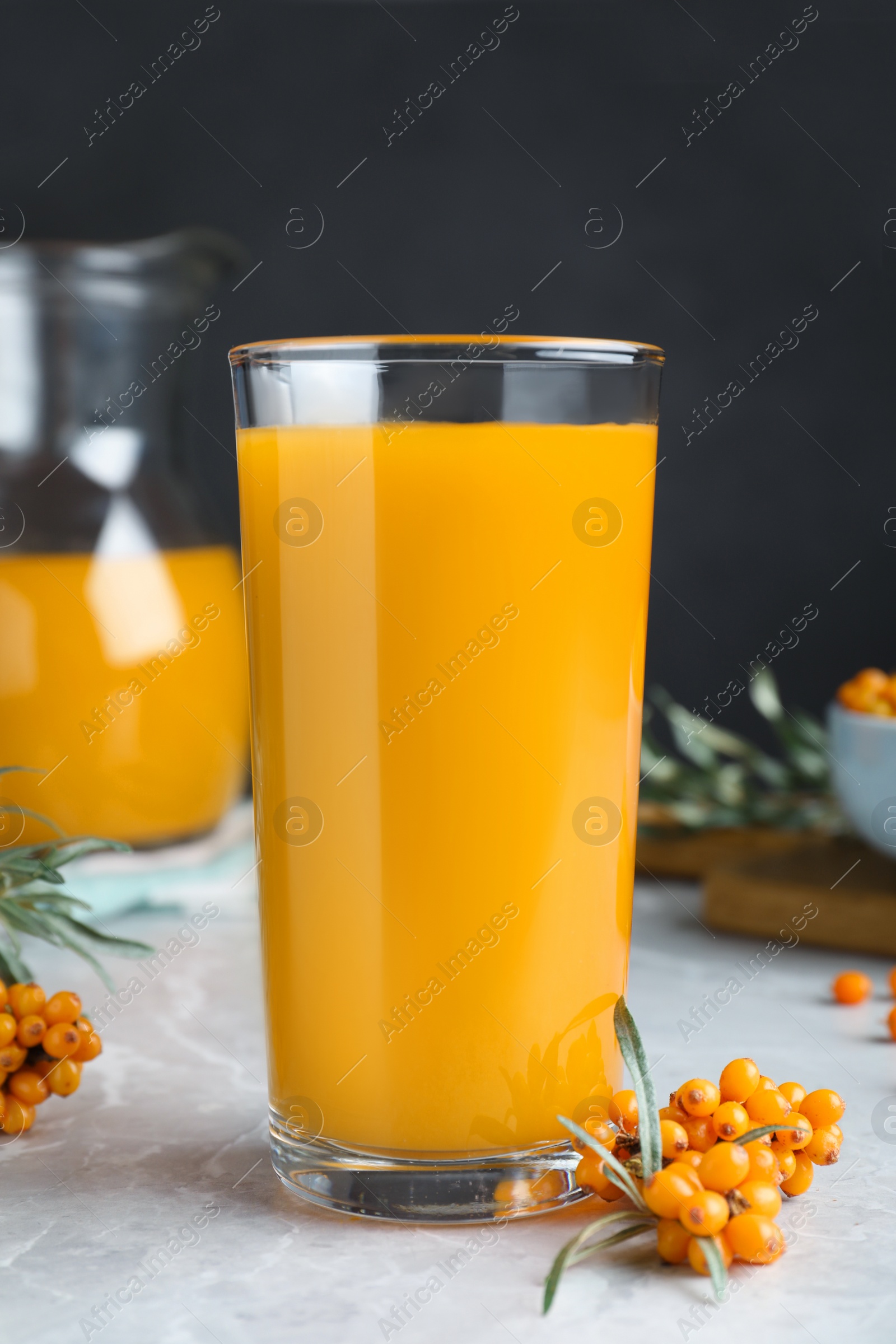 Photo of Sea buckthorn juice and fresh berries on white marble table, closeup