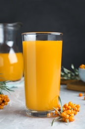 Sea buckthorn juice and fresh berries on white marble table, closeup