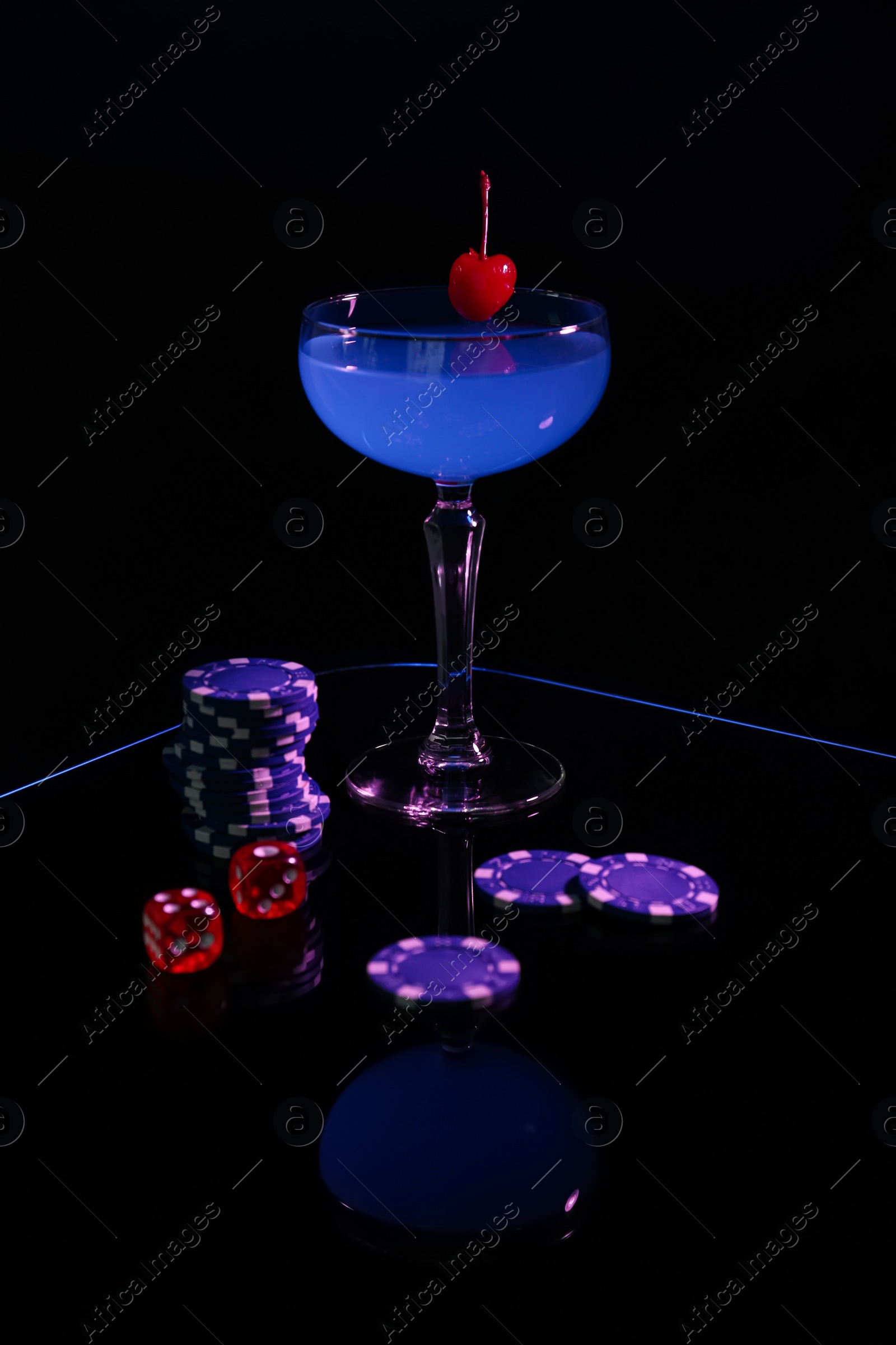 Photo of Casino chips, dice and cocktail on dark background