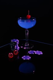 Photo of Casino chips, dice and cocktail on dark background