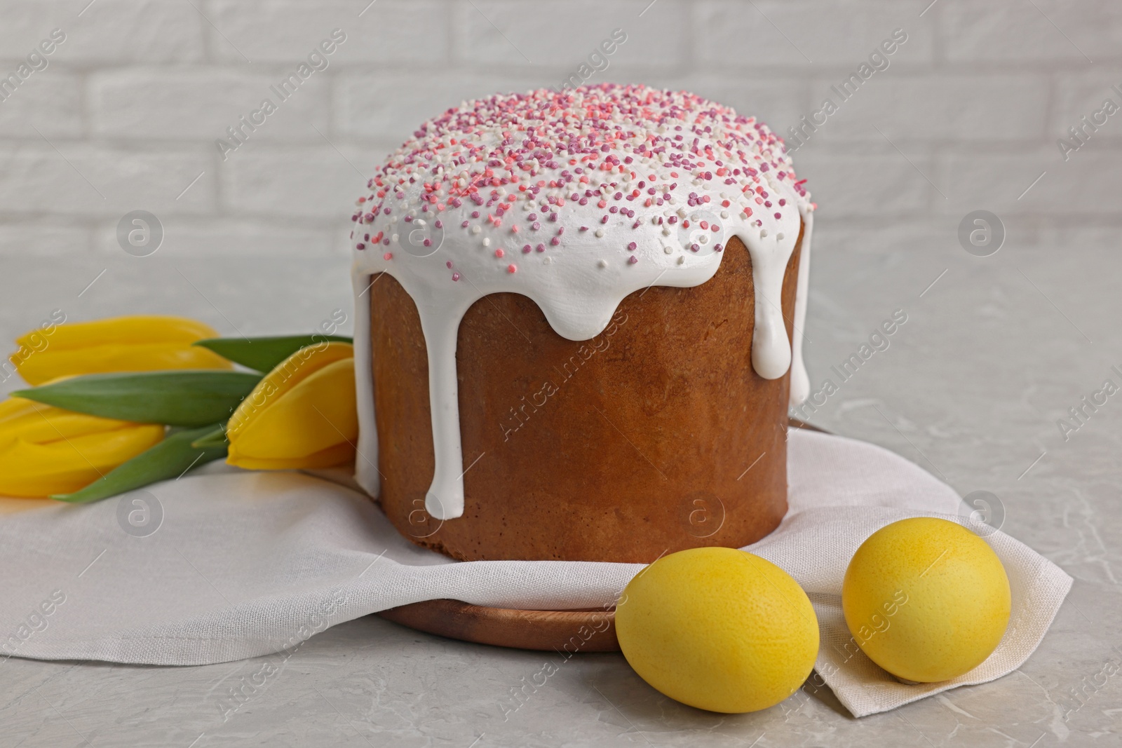 Photo of Tasty Easter cake, decorated eggs and flowers on grey table