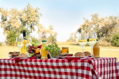 Photo of Picnic table with different tasty snacks and wine