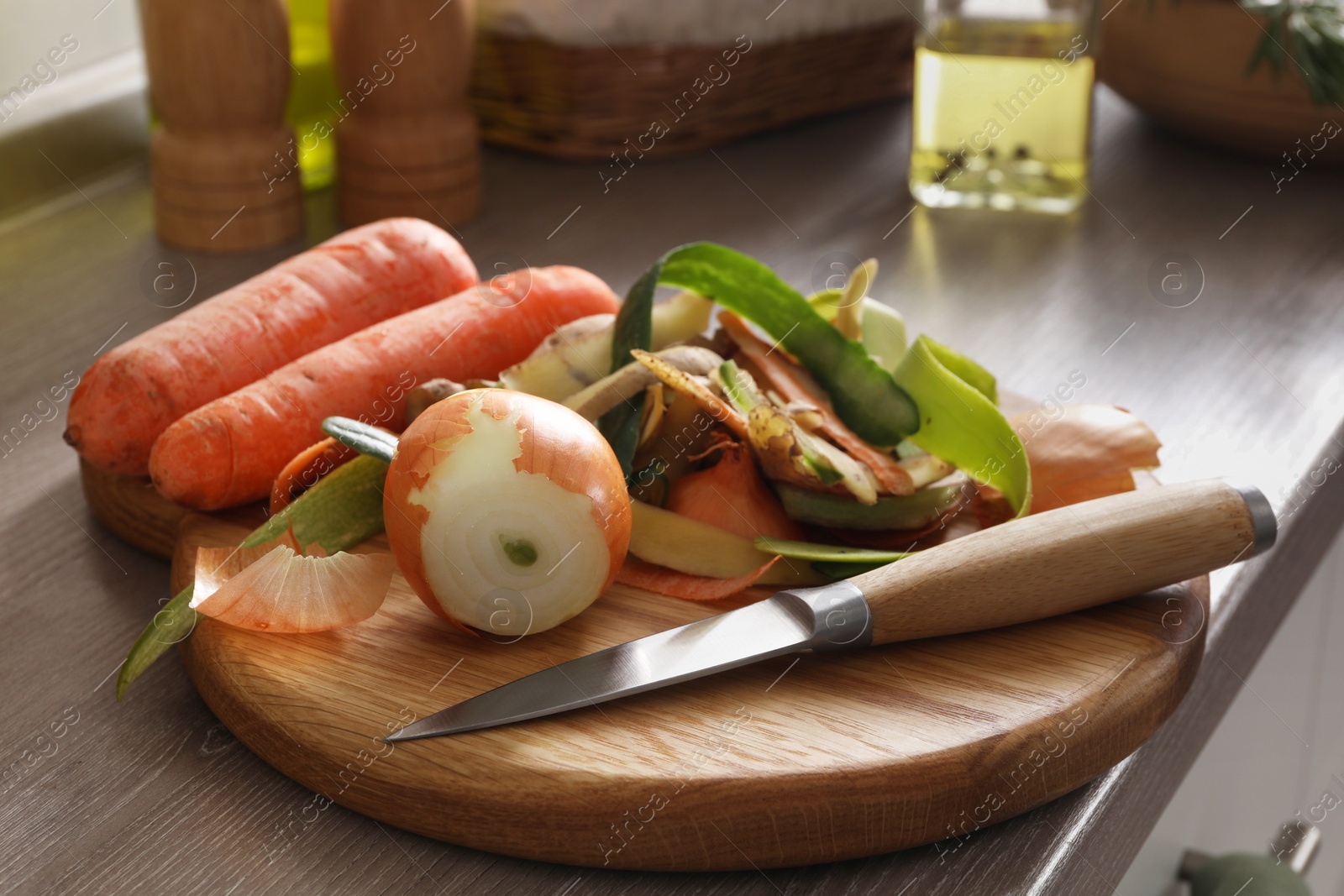 Photo of Peels of fresh vegetables and knife on wooden table, closeup