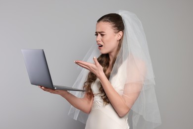 Photo of Shocked bride with laptop on gray background