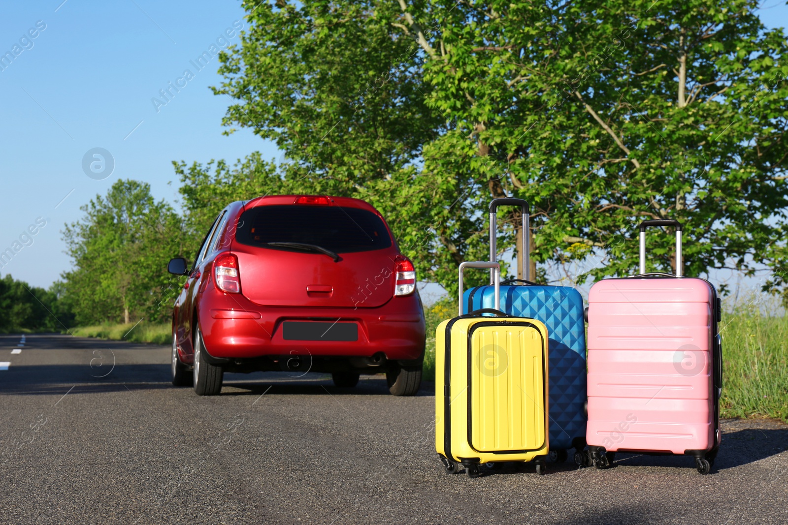 Photo of Color suitcases near family car on highway. Summer vacation