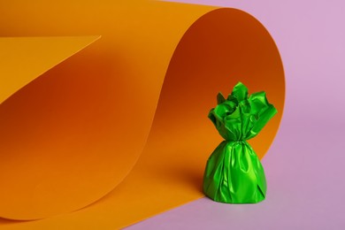 Photo of Candy in green wrapper on color background. Space for text