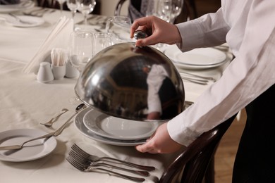 Photo of Woman setting table in restaurant, closeup. Professional butler courses