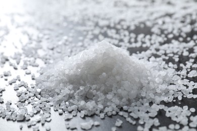 Photo of Heap of natural salt on black table, closeup