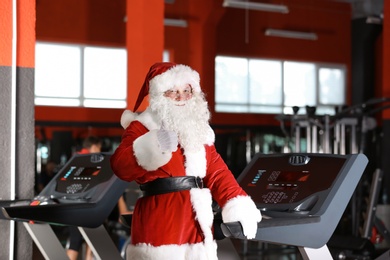 Photo of Authentic Santa Claus training on treadmill in modern gym