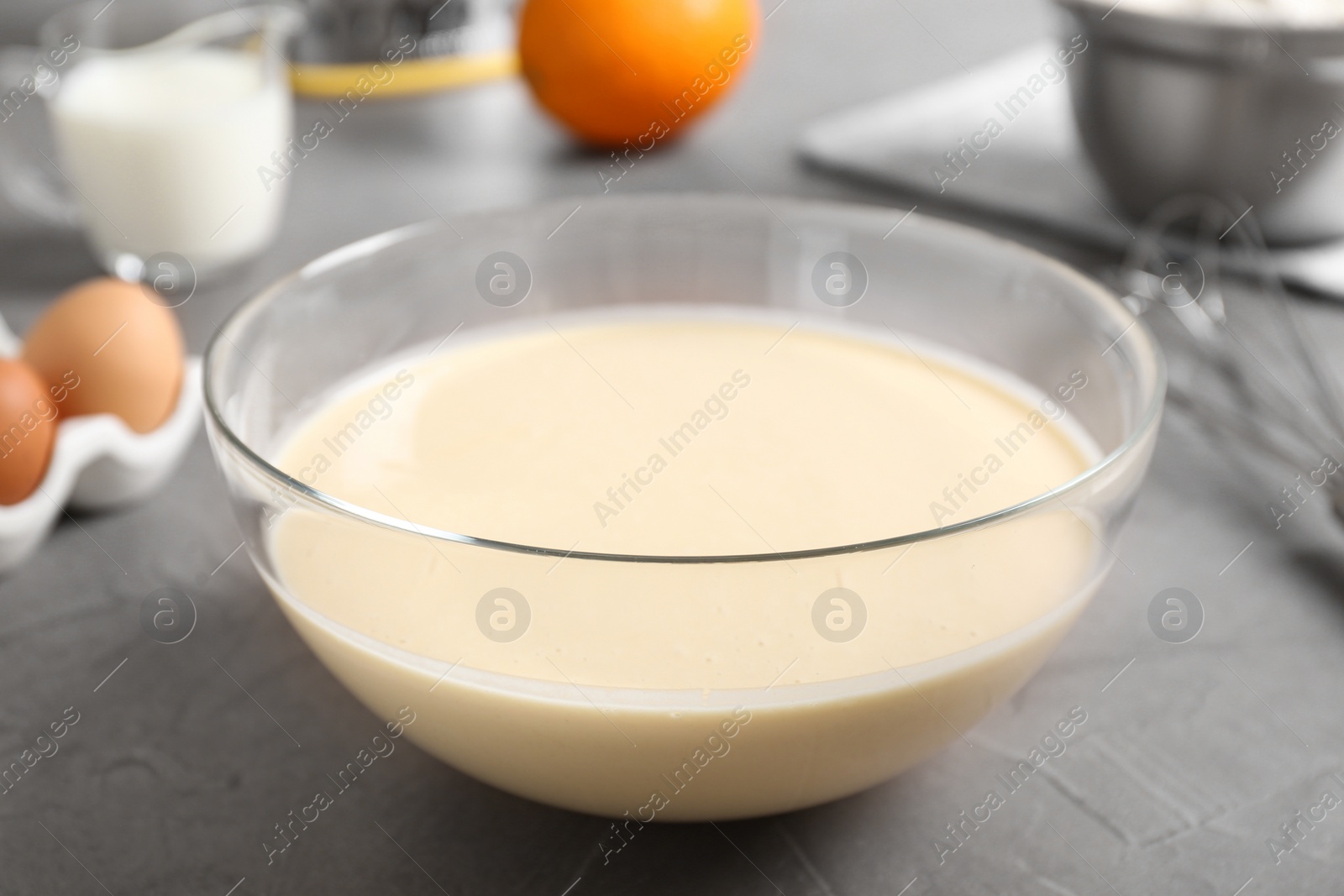 Photo of Glass bowl with batter on grey table, closeup