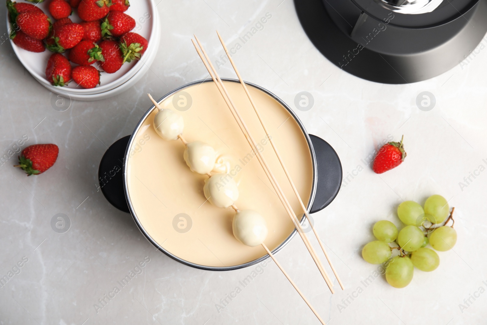 Photo of Flat lay composition with chocolate fondue in pot and berries on table