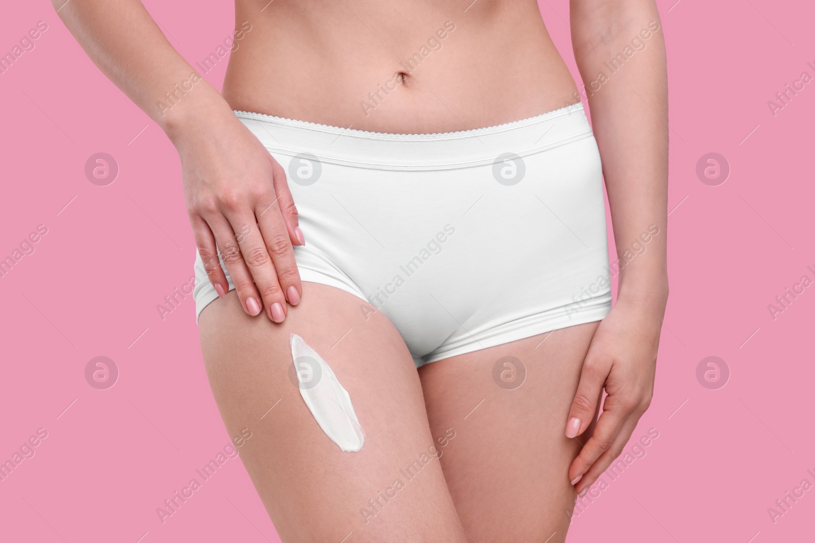 Photo of Woman with smear of body cream on her leg against pink background, closeup