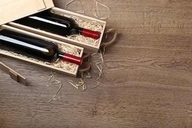 Photo of Wooden crates with expensive wine on table, flat lay. Space for text