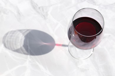 Photo of Glass of red wine served on white marble table, above view. Space for text