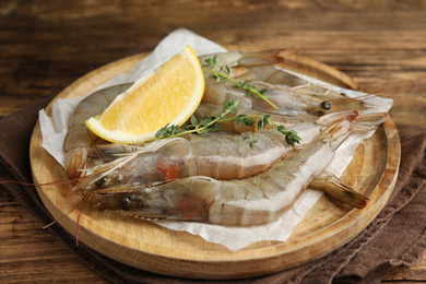 Photo of Fresh raw shrimps with lemon slice on wooden table