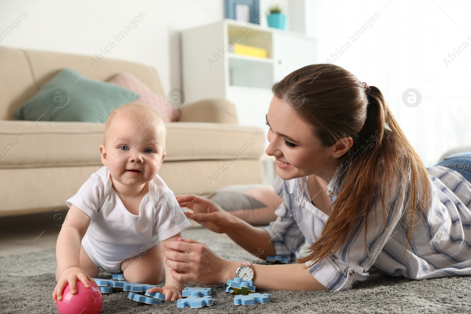 Photo of Happy mother playing with little baby on floor indoors