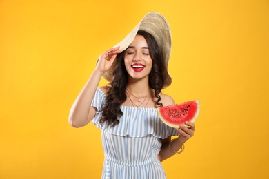 Beautiful young woman with watermelon on yellow background