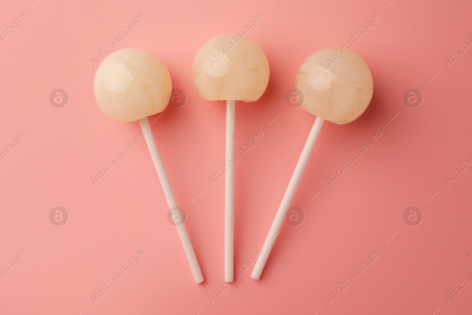 Photo of Tasty lollipops on pink background, flat lay