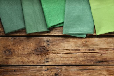 Photo of Different kitchen napkins on wooden table, flat lay. Space for text