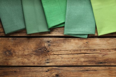 Different kitchen napkins on wooden table, flat lay. Space for text