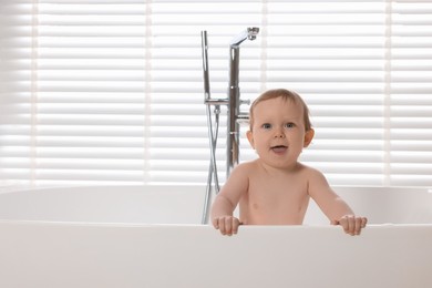 Cute little baby bathing in tub at home. Space for text