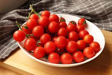Photo of Plate of ripe whole cherry tomatoes with water drops on wooden table
