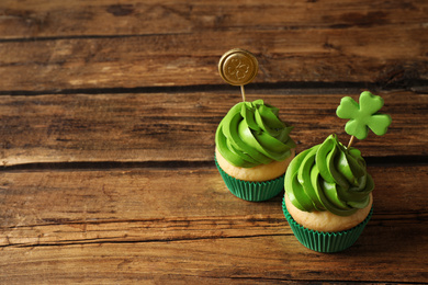 Delicious decorated cupcakes on wooden table, space for text. St. Patrick's Day celebration