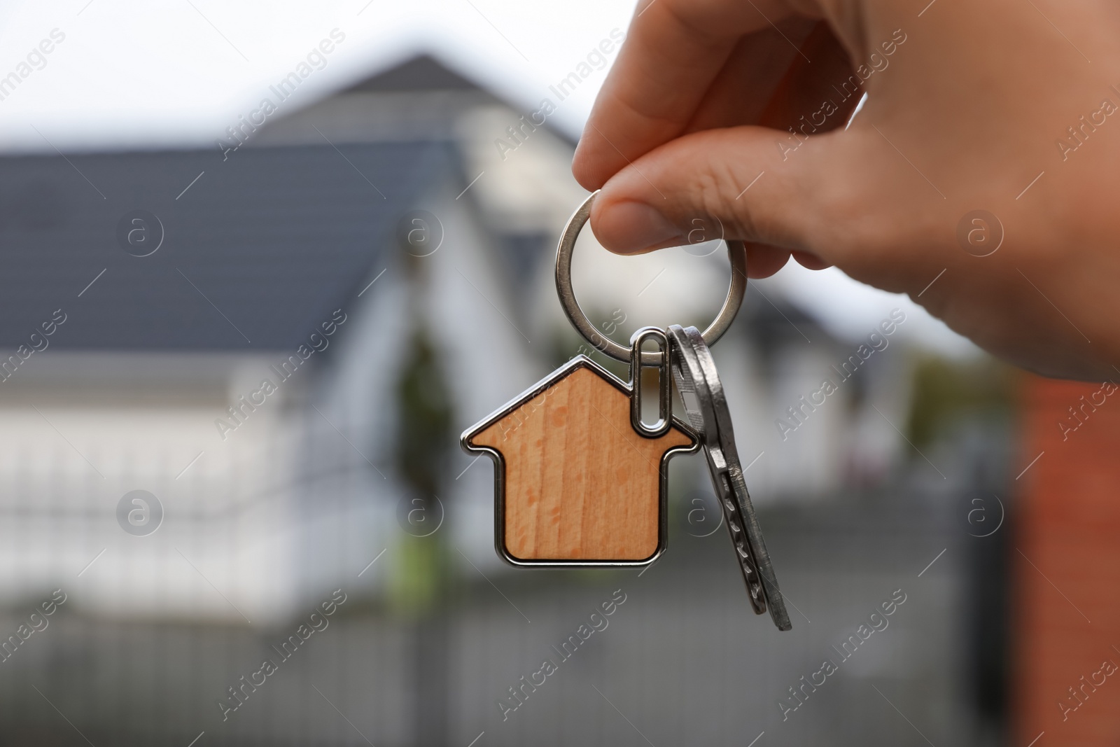 Photo of Woman holding house keys outdoors, closeup. Real estate agent