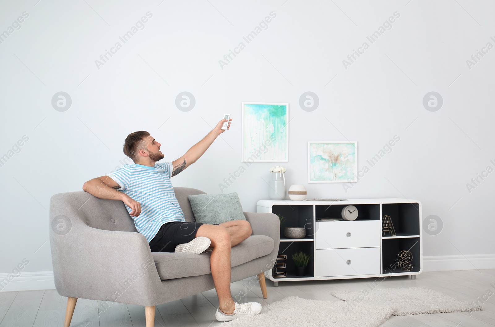 Photo of Young man with air conditioner remote at home