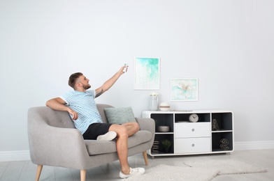 Young man with air conditioner remote at home