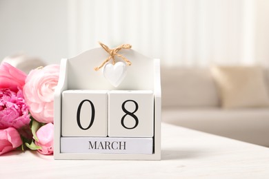 Photo of International Women's day - 8th of March. Block calendar and bouquet of beautiful flowers on white wooden table