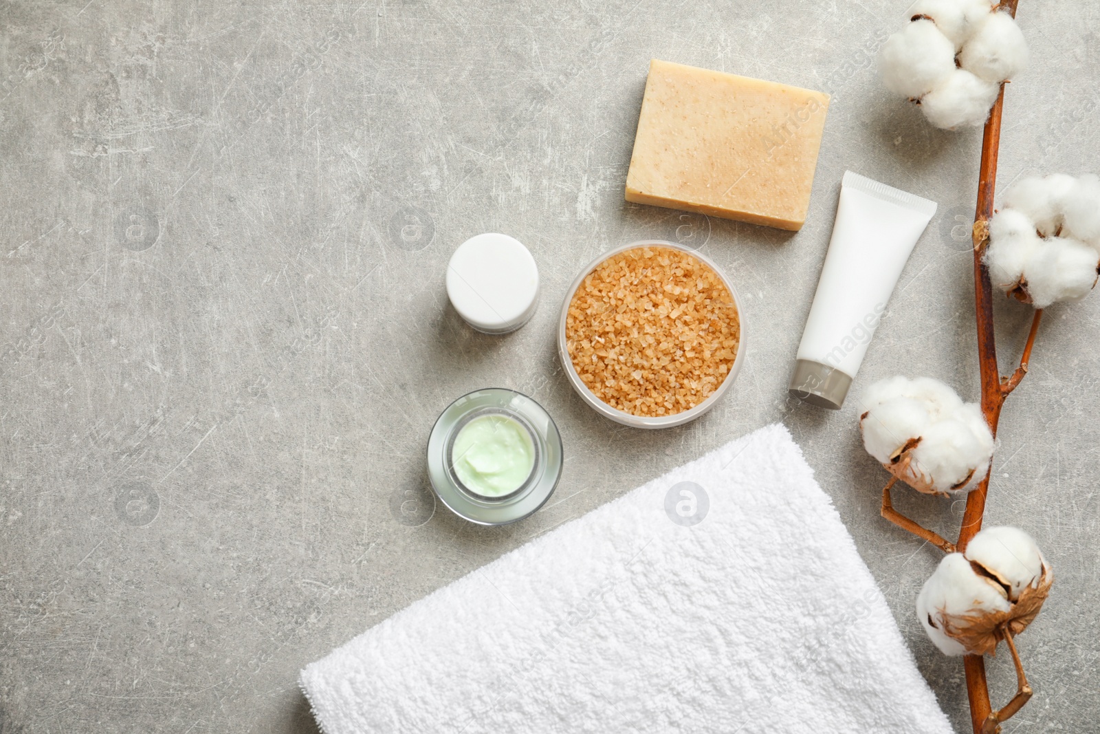 Photo of Flat lay composition with spa cosmetics and towel on grey background