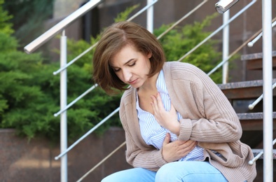 Mature woman having heart attack on stairs, outdoors