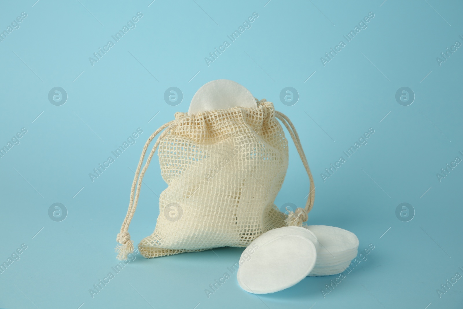 Photo of Bag with cotton pads on light blue background