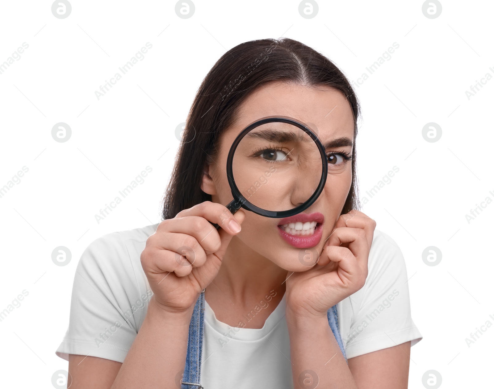 Photo of Confused young woman looking through magnifier glass on white background