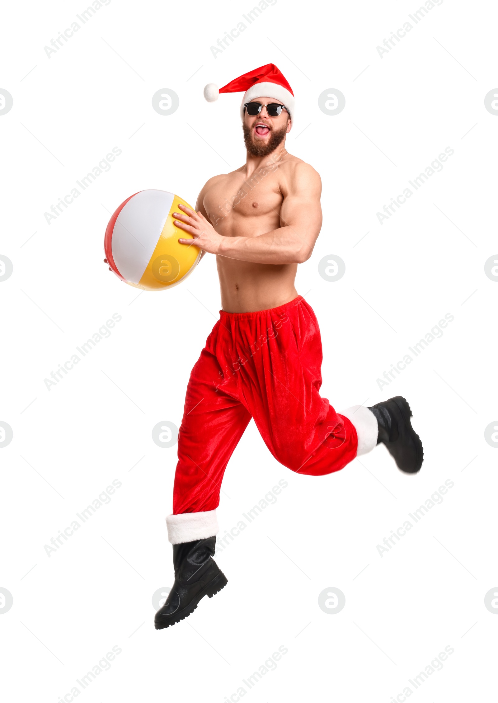 Photo of Muscular young man in Santa hat with ball jumping on white background
