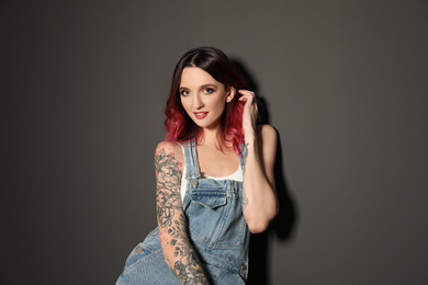 Beautiful woman with tattoos on body against black background