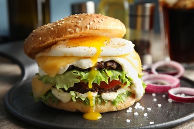 Photo of Tasty burger with fried egg on tray against blurred background