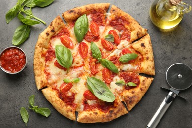 Delicious Margherita pizza, ingredients and cutter on grey table, top view