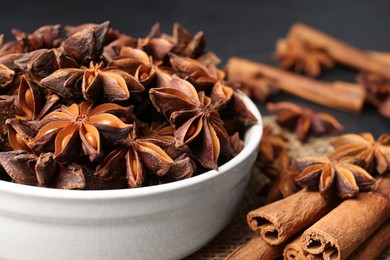 Photo of Bowl with aromatic anise stars and cinnamon sticks on table, closeup