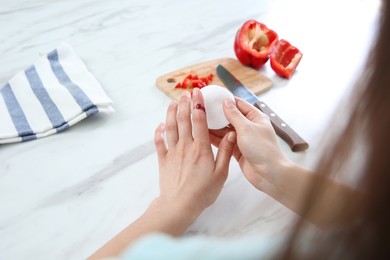 Photo of Woman cut finger while cooking at white marble table, closeup