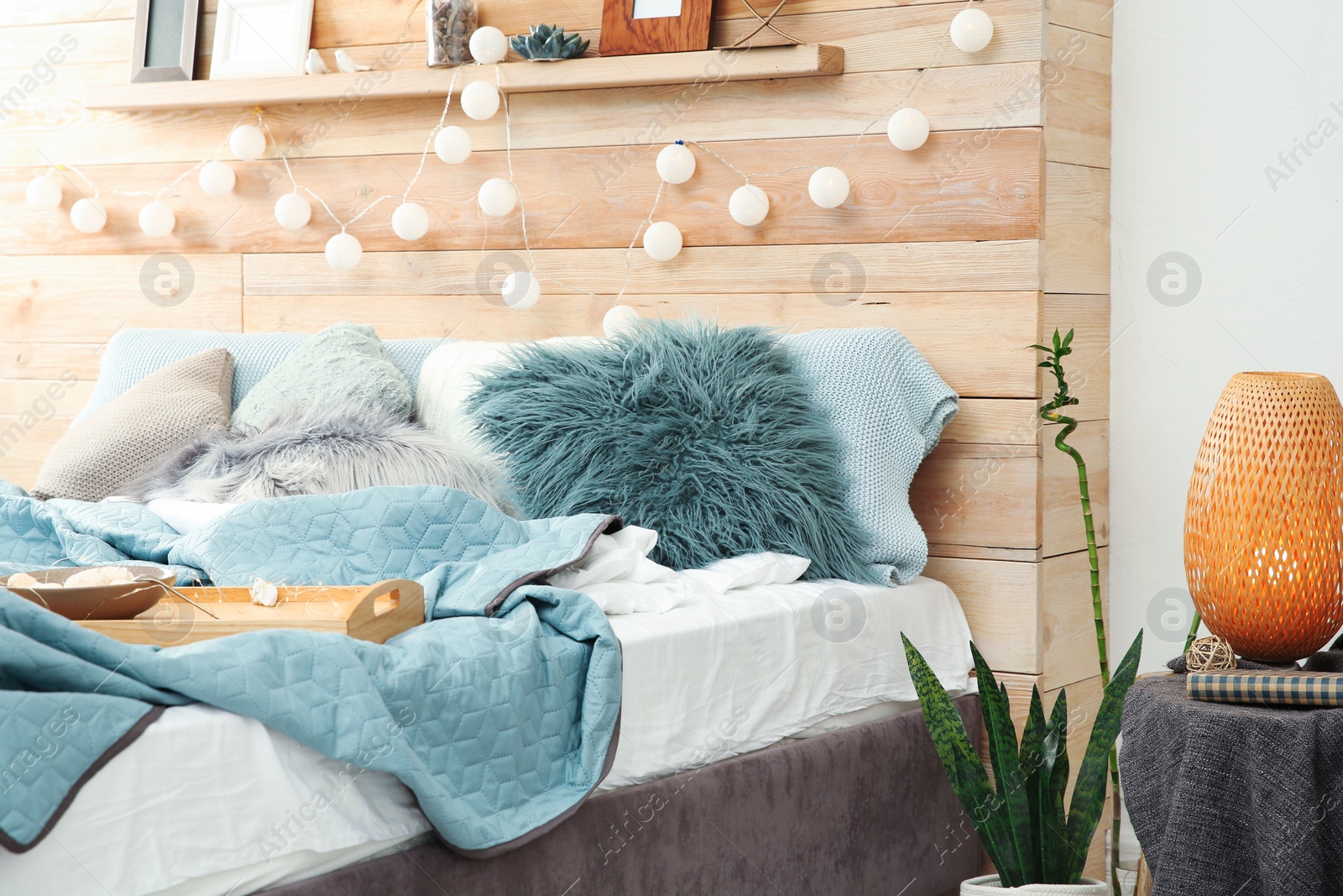 Photo of Different pillows and tray with breakfast on bed in room. Idea for interior decor