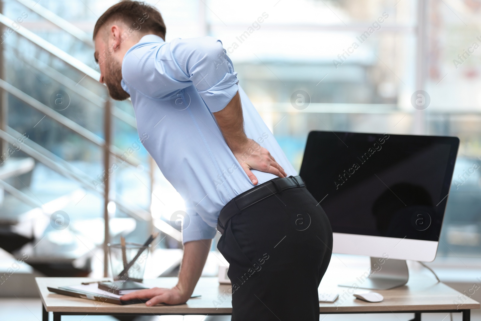 Photo of Businessman suffering from back pain at workplace