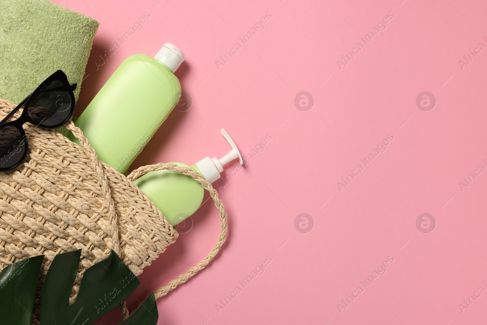 Photo of Flat lay composition with beach bag, sunglasses and bottles of skin care products on pink background. Space for text