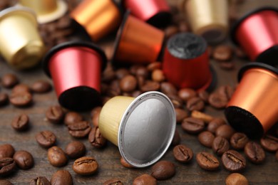 Photo of Many coffee capsules and beans on wooden table, closeup