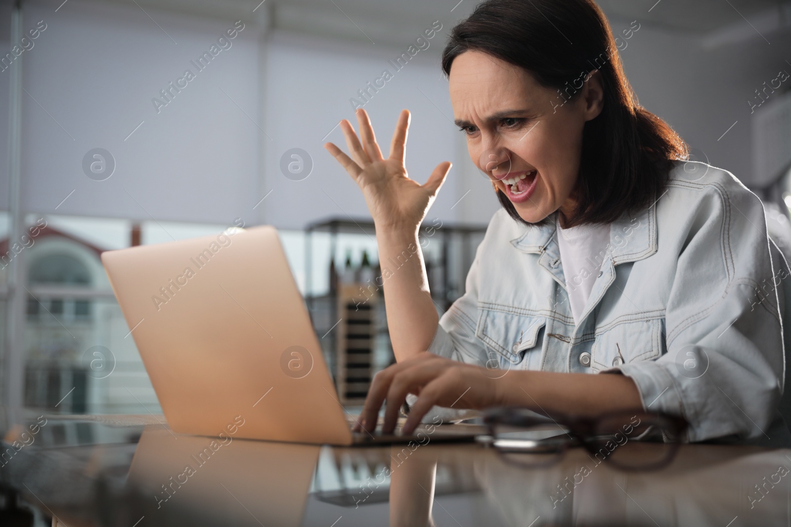 Photo of Emotional woman working on laptop in office. Online hate concept