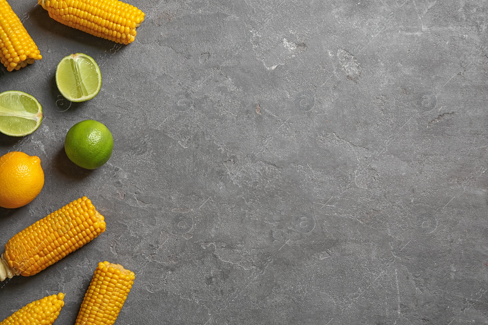 Photo of Flat lay composition with corn cobs and citrus fruits on grey background. Space for text