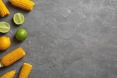 Flat lay composition with corn cobs and citrus fruits on grey background. Space for text